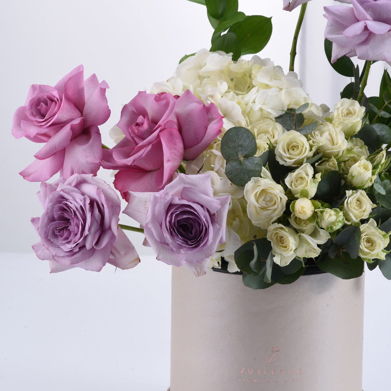 Pastel pink, lavender, and cream roses with hydrangeas in elegant blush vase.