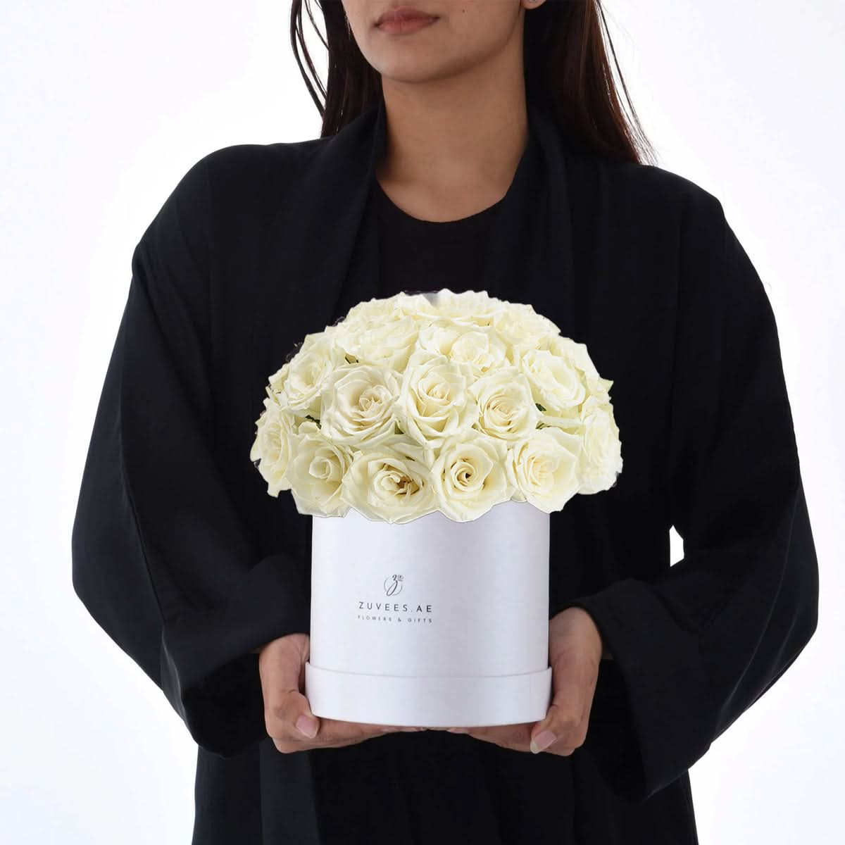 Elegant white roses in sleek box, held by person in black attire.