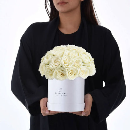 Elegant white roses in sleek box, held by person in black attire.