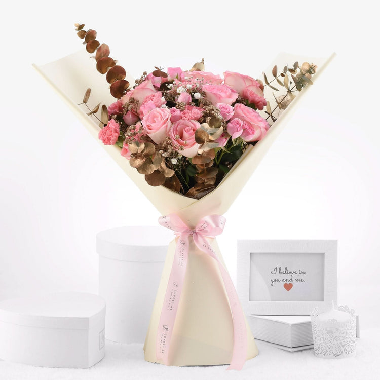 Soft pink roses and eucalyptus wrapped in cream paper with pink ribbon.