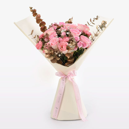 Soft pink roses, gold eucalyptus, and baby’s breath wrapped in cream paper with pink ribbon.
