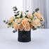Elegant peach roses and carnations in matte black box with gold logo.