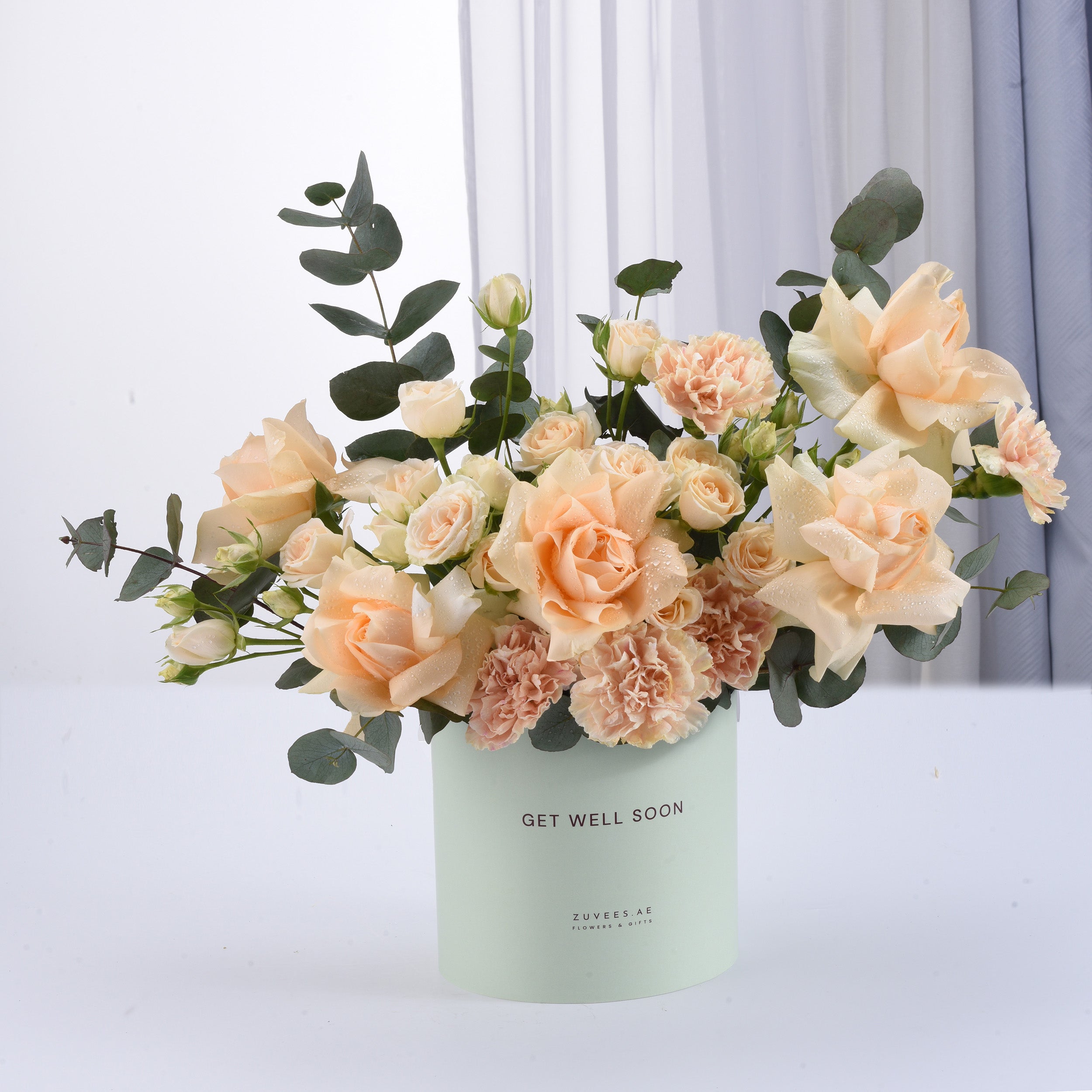 Pastel peach roses and carnations in mint "Get Well Soon" cylinder vase.
