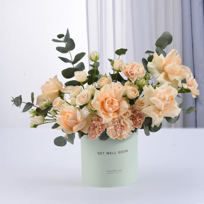Pastel peach roses and carnations in mint "Get Well Soon" cylinder vase.