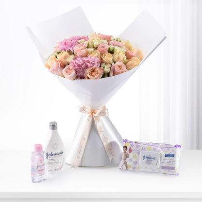 Soft pink roses bouquet with Johnson’s baby care products on white surface.