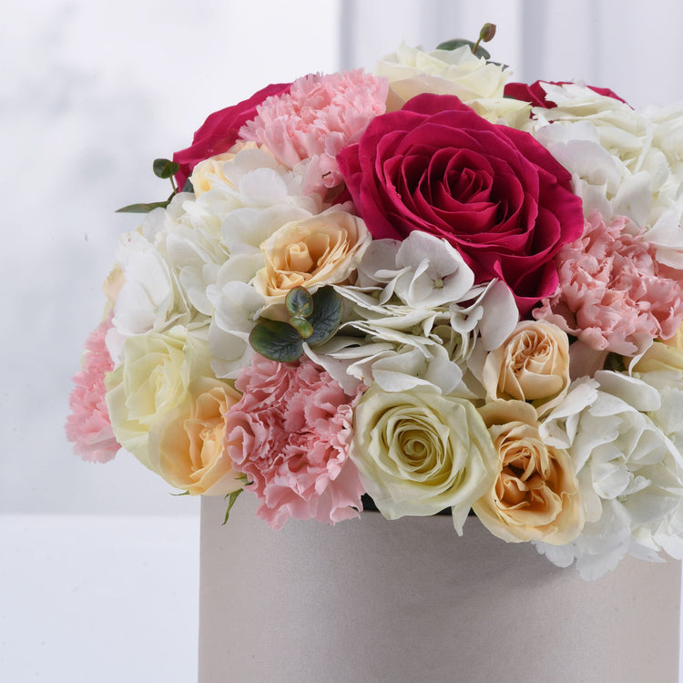 Vibrant pink, white, and cream roses and carnations in elegant box arrangement.