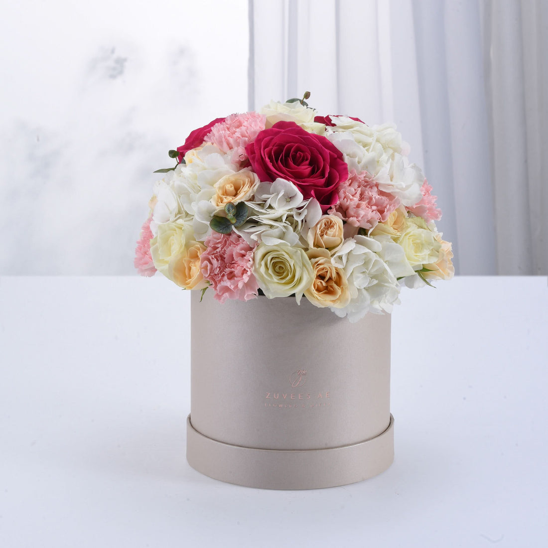 Elegant pastel floral arrangement in matte beige hat box with rose and carnation bouquet.