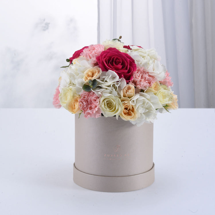 Elegant pastel floral arrangement in matte beige hat box with rose and carnation bouquet.