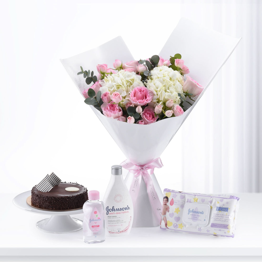 Pink roses and hydrangeas bouquet with chocolate cake and Johnson’s baby care products.