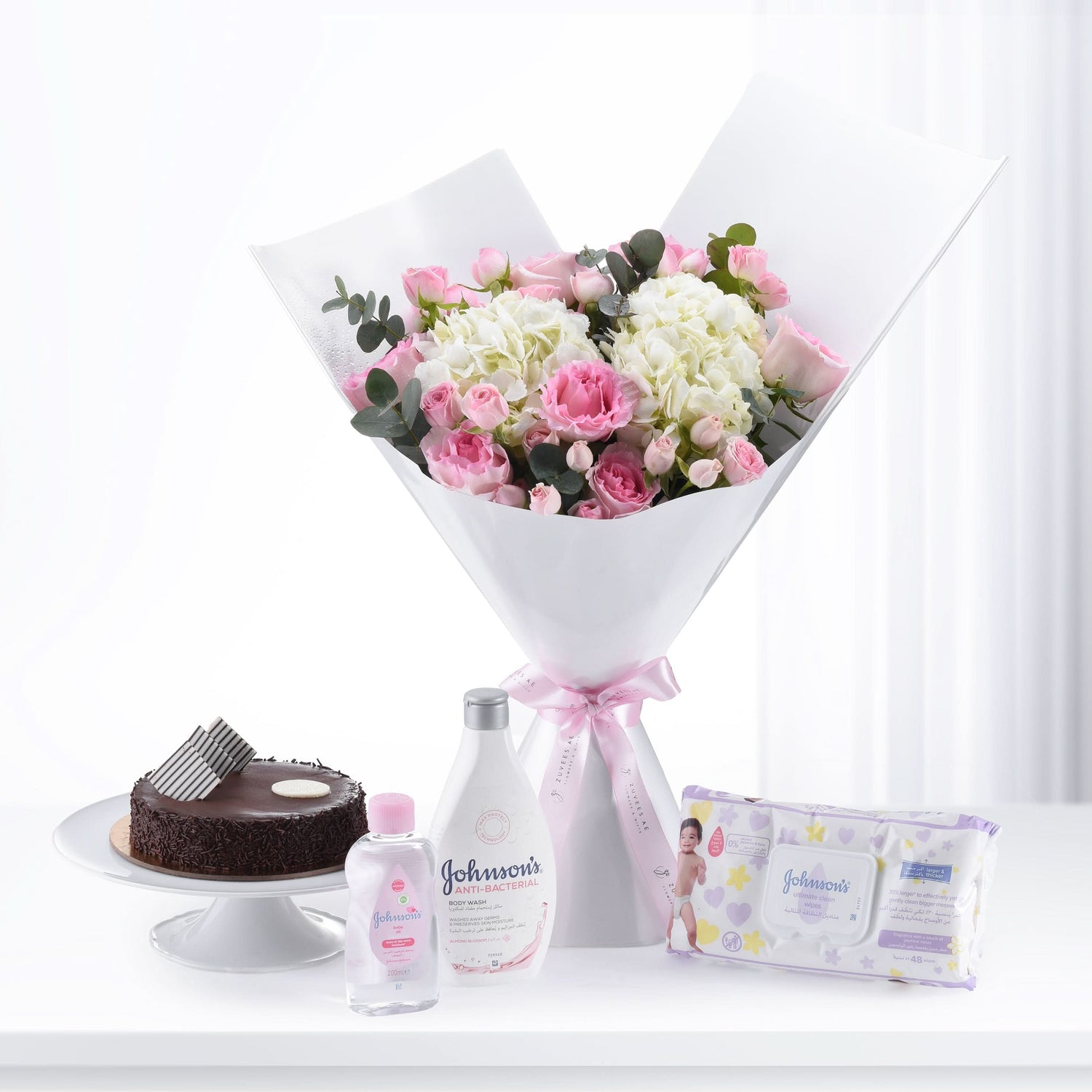 Pink roses and hydrangeas bouquet with chocolate cake and Johnson’s baby care products.