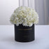 Elegant white hydrangeas in matte black box, gold "Happy Anniversary" text, minimalist luxury floral gift.