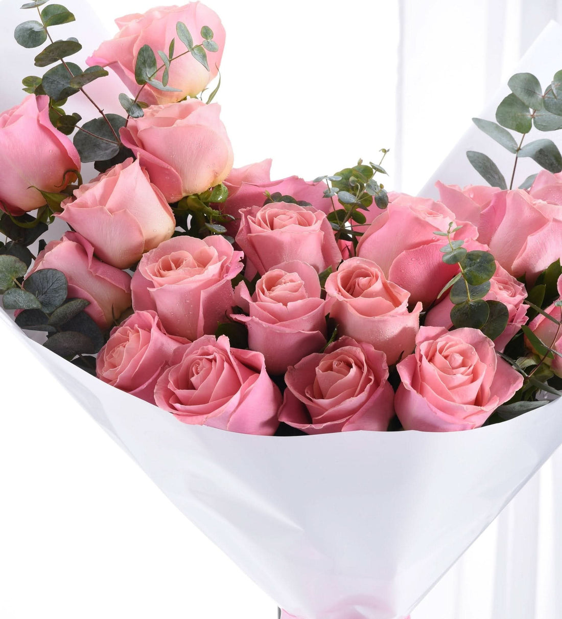 Soft pink roses with dewdrops, wrapped in crisp white paper, accented by lush green eucalyptus.