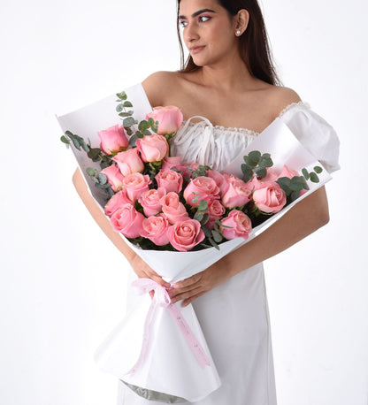 Soft pink roses elegantly wrapped in white paper with delicate pink ribbon.