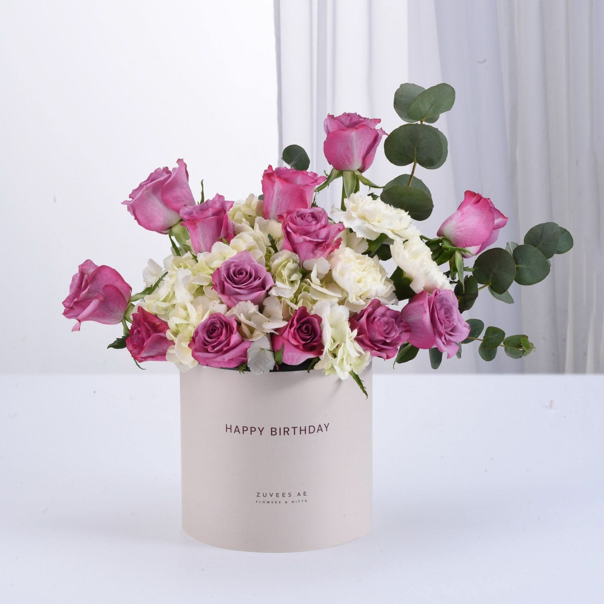 Pink roses, white hydrangeas, and eucalyptus in beige "Happy Birthday" box.