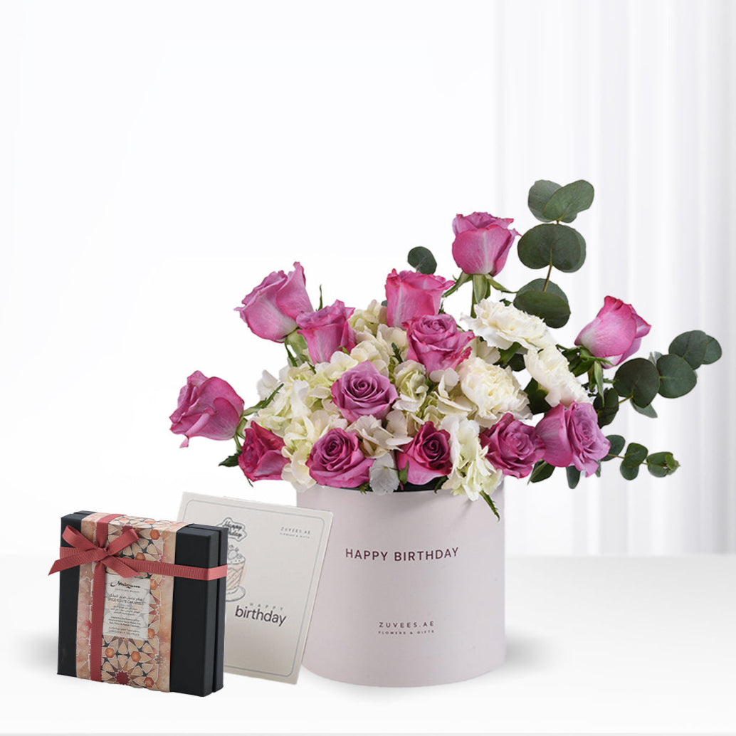 Pink roses, white blooms, eucalyptus in pastel box with birthday card and chocolate gift.