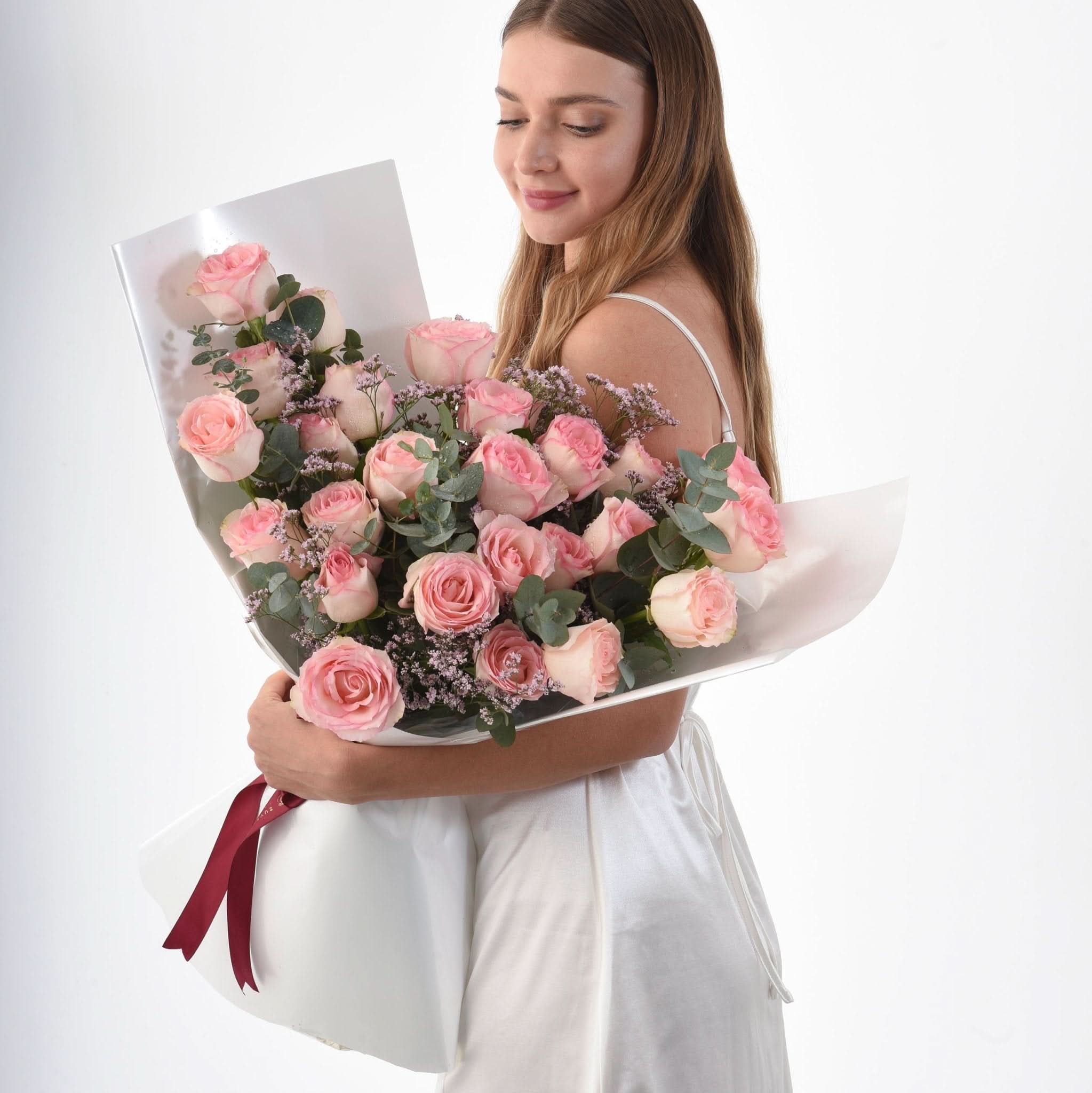 Soft pink roses, eucalyptus, and baby’s breath in white wrap with burgundy ribbon.