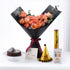 Black-wrapped peach roses, chocolate cake, party hat, and candles for birthday celebration.