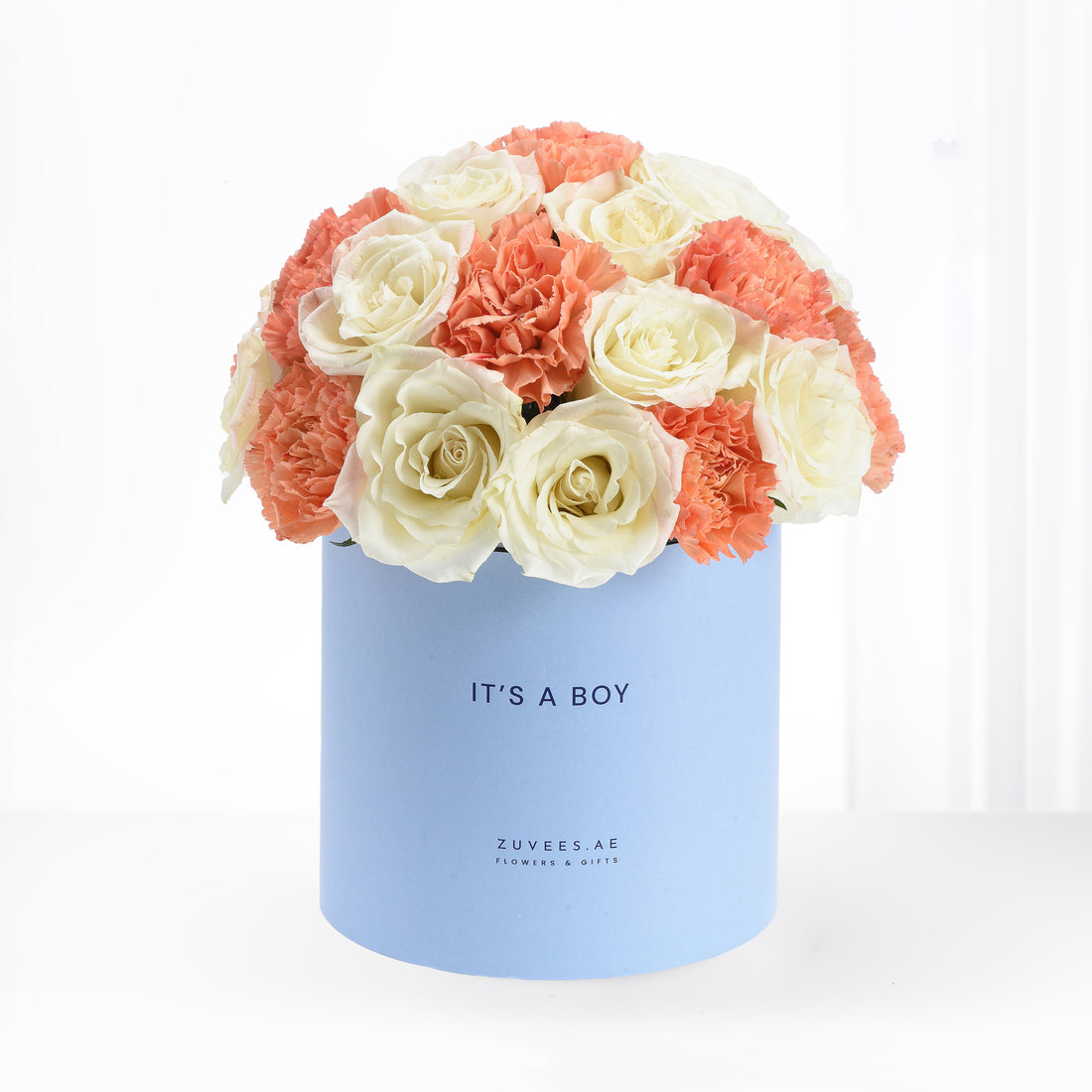 Pastel blue box holds creamy white roses and coral carnations, celebrating "It&
