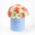 Pastel blue box holds creamy white roses and coral carnations, celebrating "It&