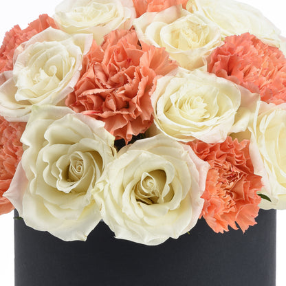 Cream roses and coral carnations in sleek black vase.
