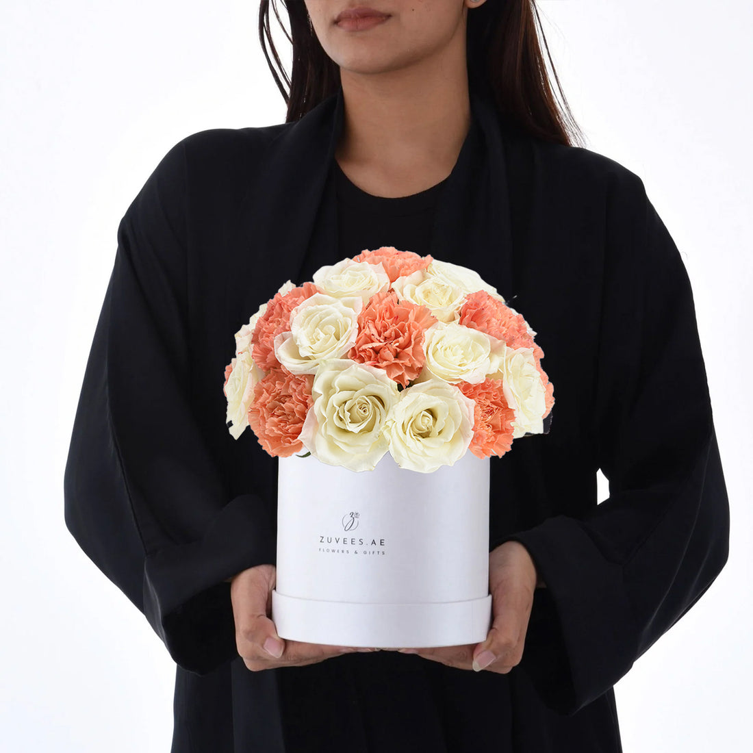 White box holds creamy roses and coral carnations, elegant gift presentation.