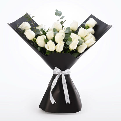 Elegant white rose bouquet wrapped in glossy black paper with silver ribbon.