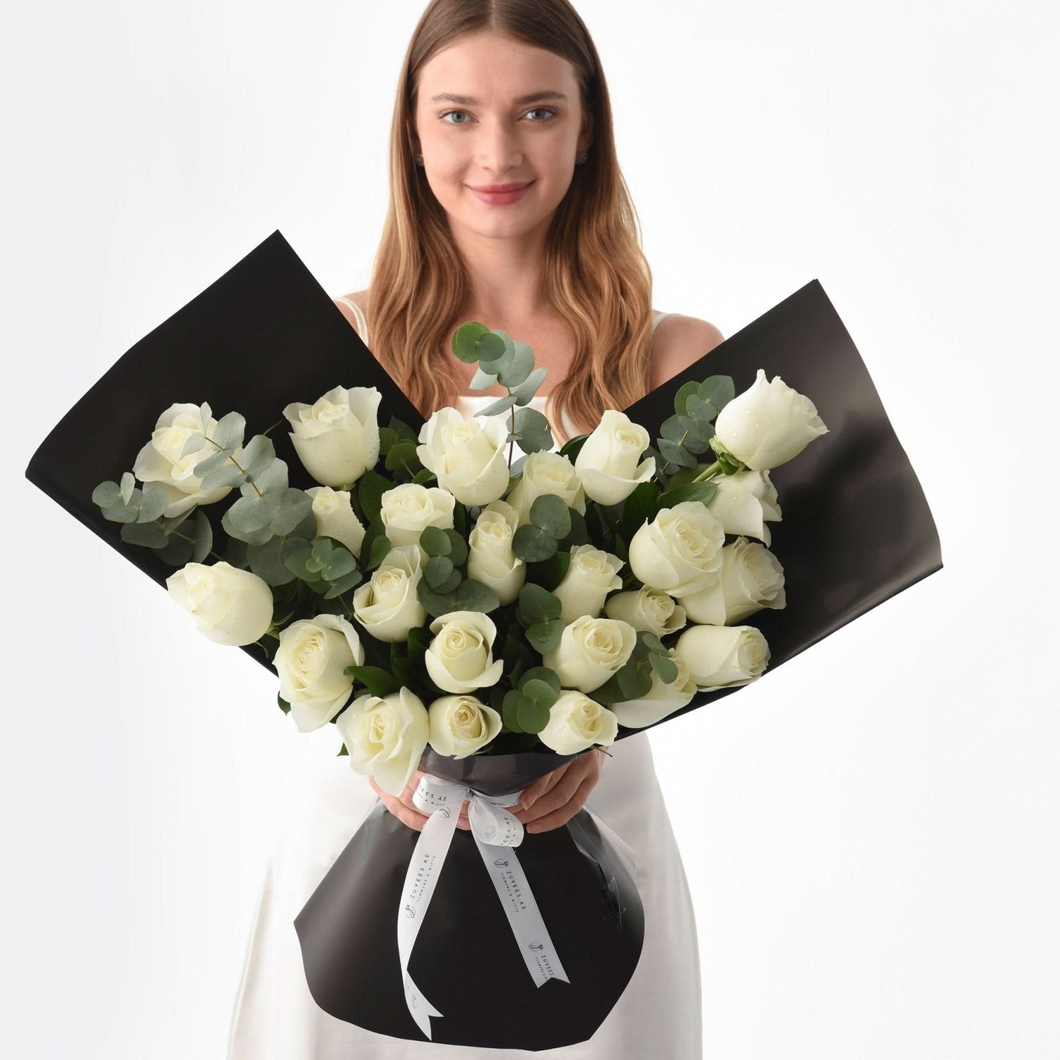Elegant white roses wrapped in matte black paper with silver ribbon.