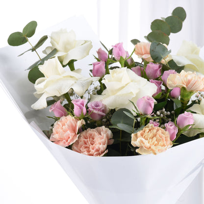 White, pink, and peach roses with eucalyptus in a sleek white box, dew-kissed petals.