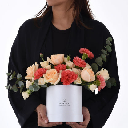 Elegant peach roses, coral carnations, and eucalyptus in a white Zuvees gift box.