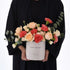 Soft peach roses and coral carnations in white box reading “Happy Birthday”.
