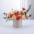 Soft peach roses and coral carnations in sleek silver box.