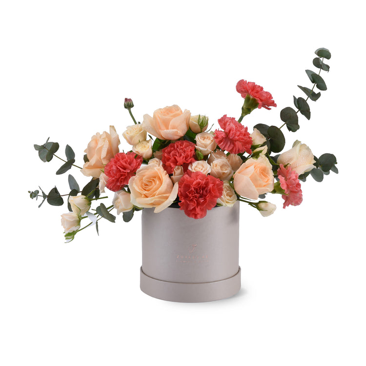 Soft peach roses and coral carnations in sleek silver box.