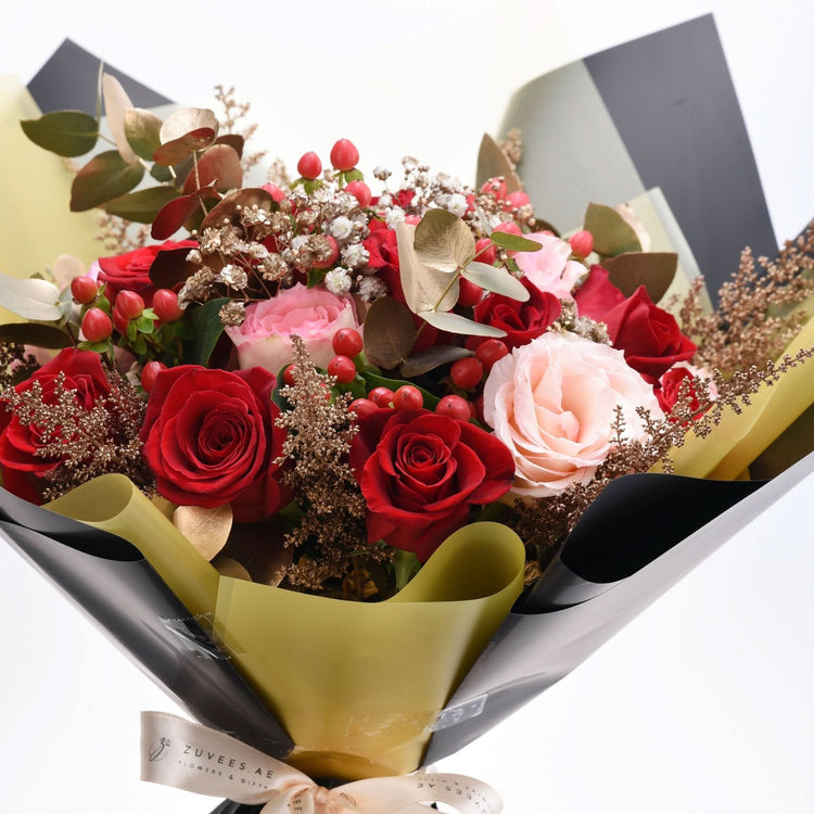 Luxurious red and blush rose bouquet wrapped in black and gold paper.