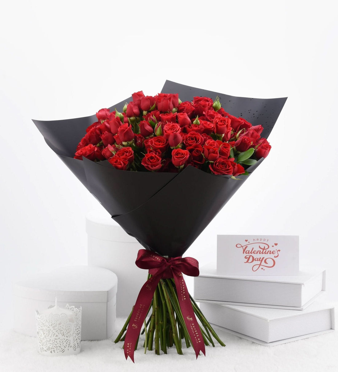 Luxurious red roses in sleek black wrap, Valentine’s Day card nearby.