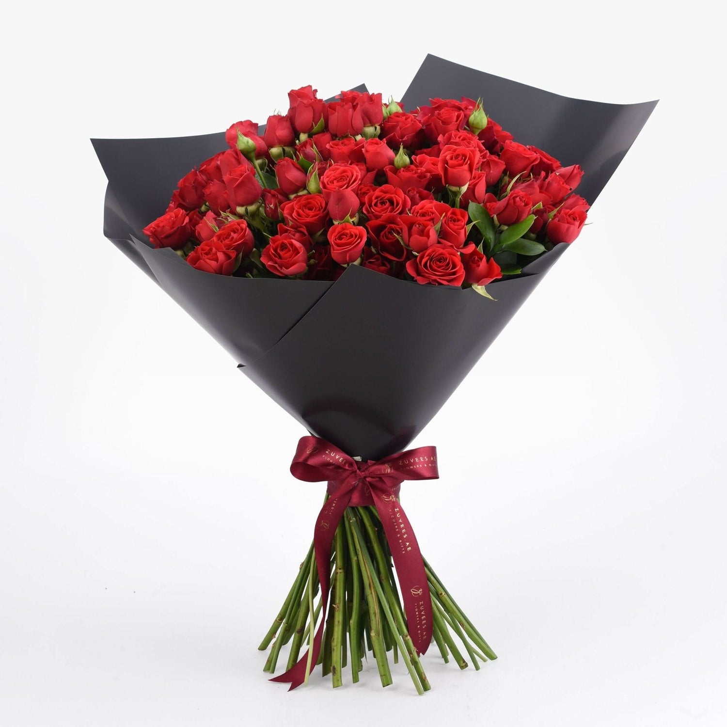 Vibrant red roses in sleek black paper, tied with burgundy ribbon.