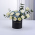 Elegant white roses, blue hydrangeas, eucalyptus in black "Happy Anniversary" box, gold lettering, minimalist white background.