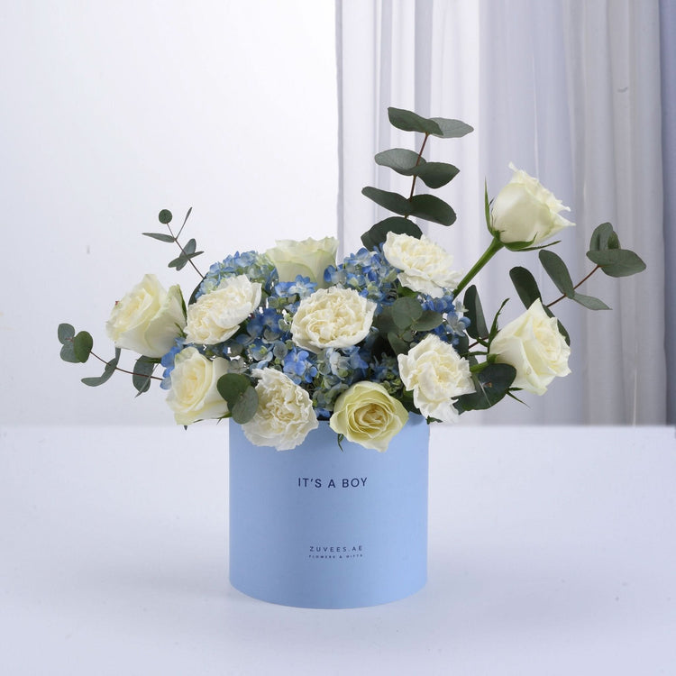 Light blue box holds white roses and hydrangeas, eucalyptus, celebrating “It’s a Boy.”