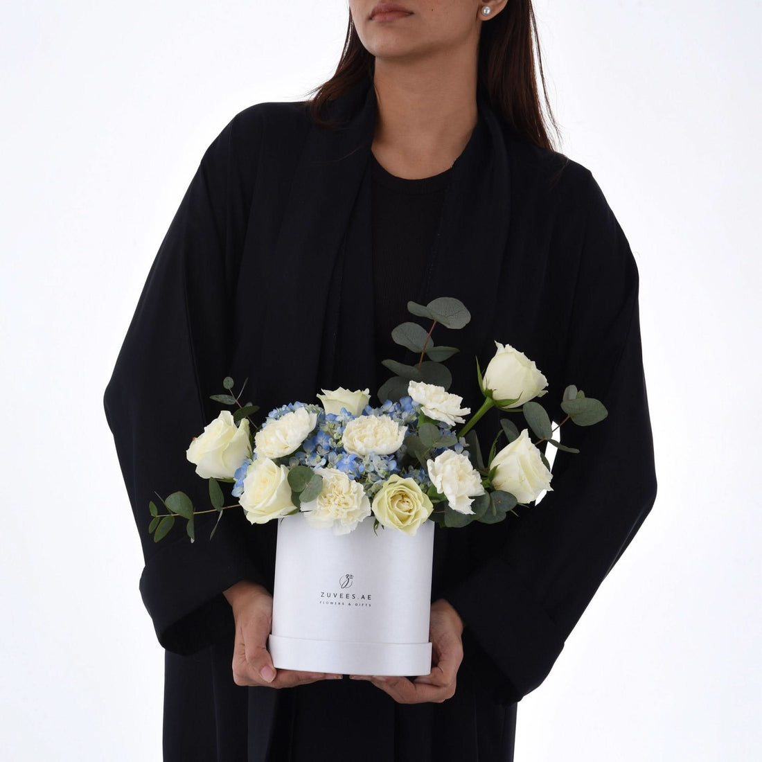 Elegant white roses and blue hydrangeas in minimalist white box.