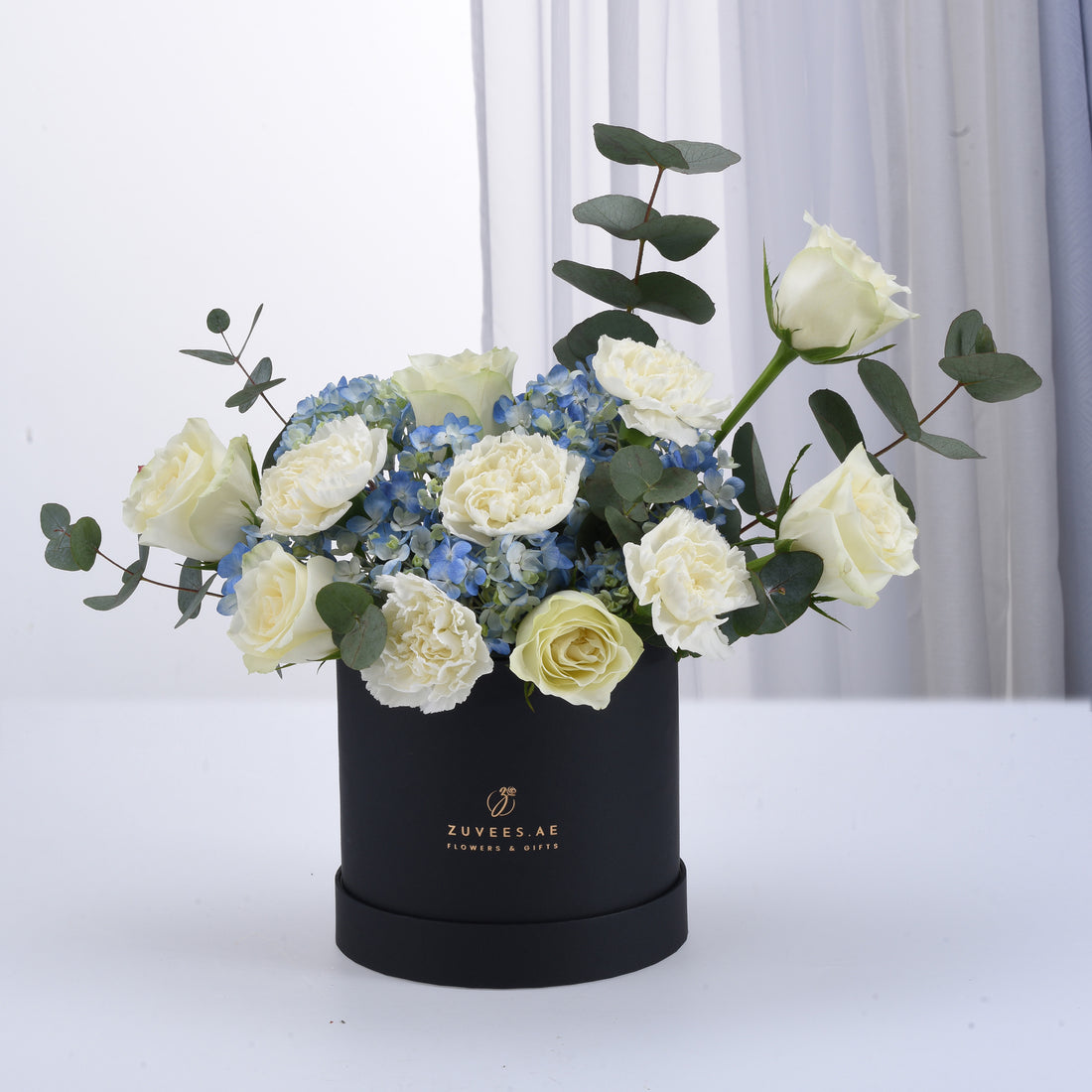 Elegant white roses and blue hydrangeas in matte black box.