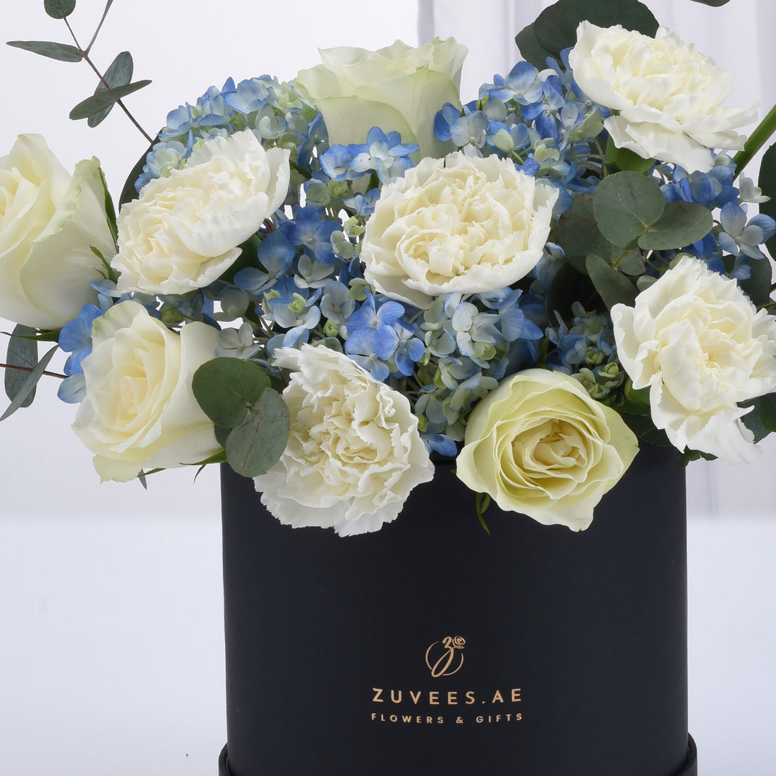 Elegant white roses and blue hydrangeas in sleek black gift box.