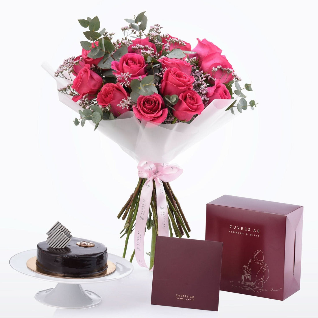 Vibrant pink roses with eucalyptus, chocolate cake, and burgundy gift boxes for elegant gifting.