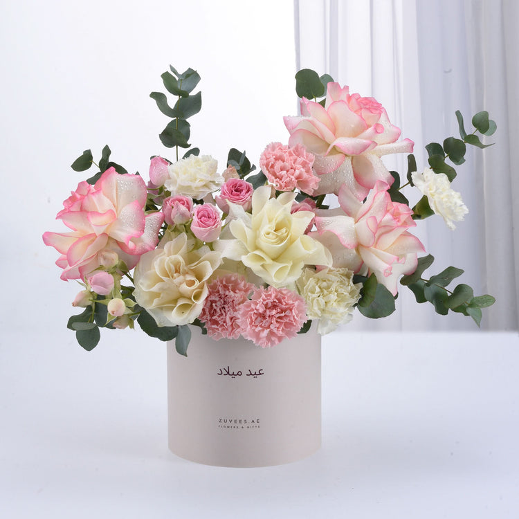 Pink and cream roses with eucalyptus in elegant white gift box, dew-kissed petals.