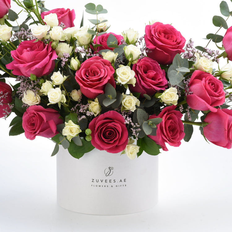 Vibrant pink and white roses with eucalyptus in a sleek white Zuvees.AE gift box.