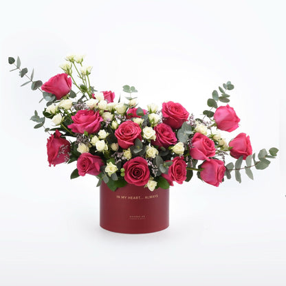Vibrant pink and white roses in elegant red box with gold text.