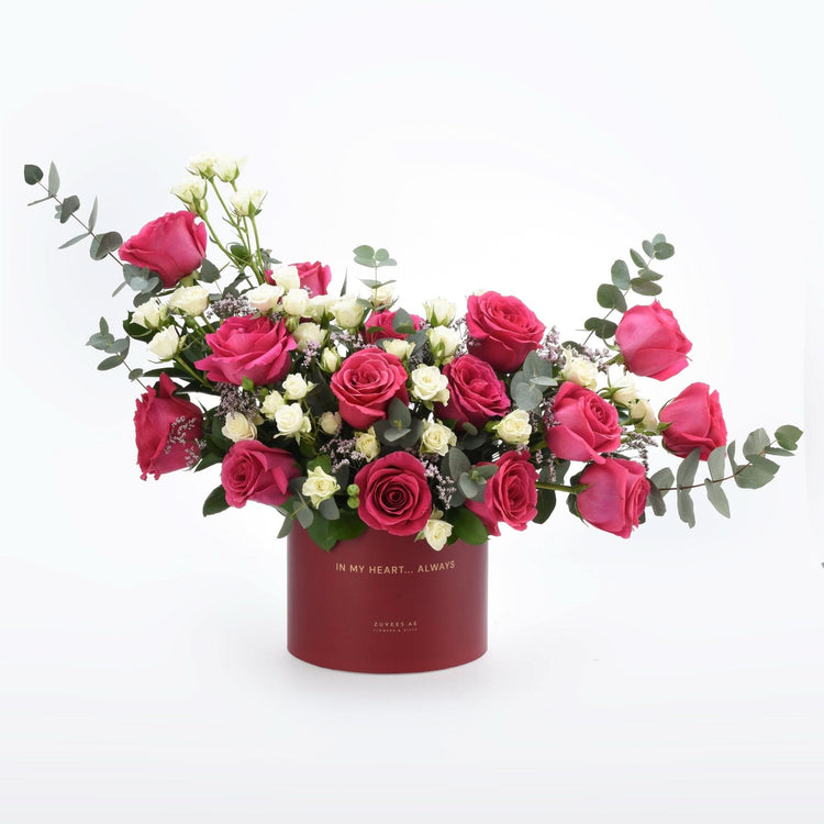 Vibrant pink and white roses in elegant red box with gold text.