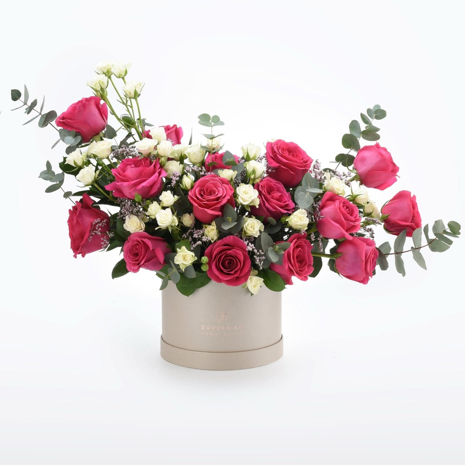 Vibrant pink and white roses in elegant taupe box with eucalyptus.