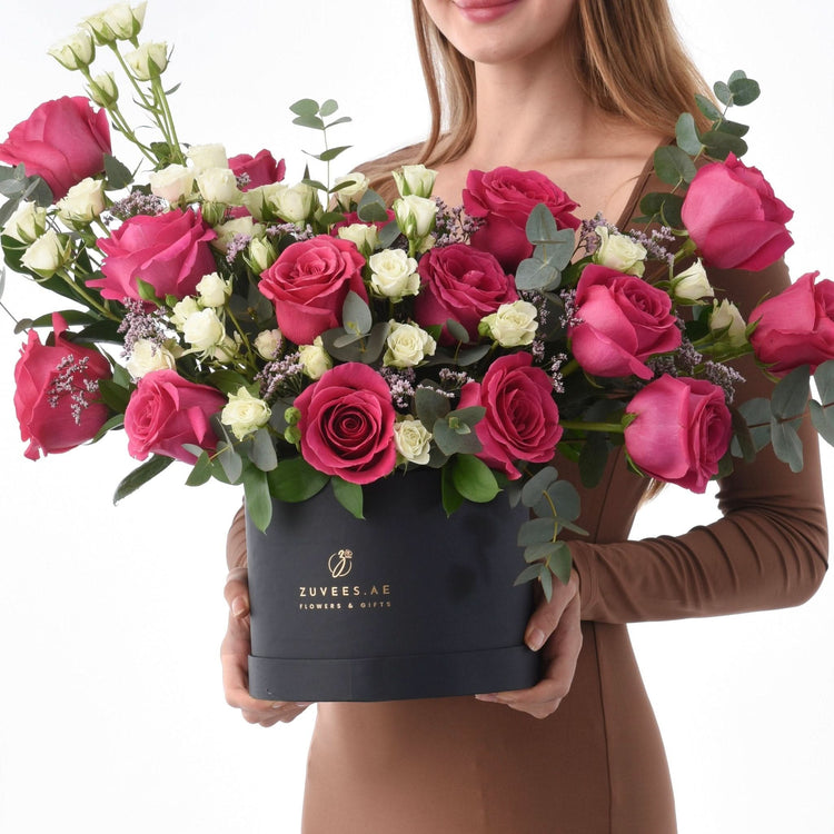 Elegant black box filled with vibrant pink and white roses, accented with eucalyptus.