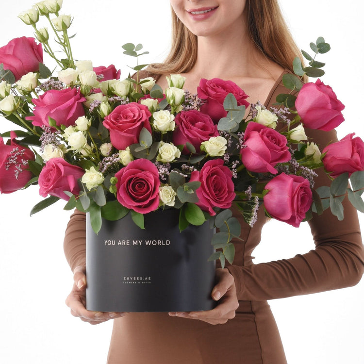 Black box holds vibrant pink and white roses, eucalyptus, with "You Are My World" message.