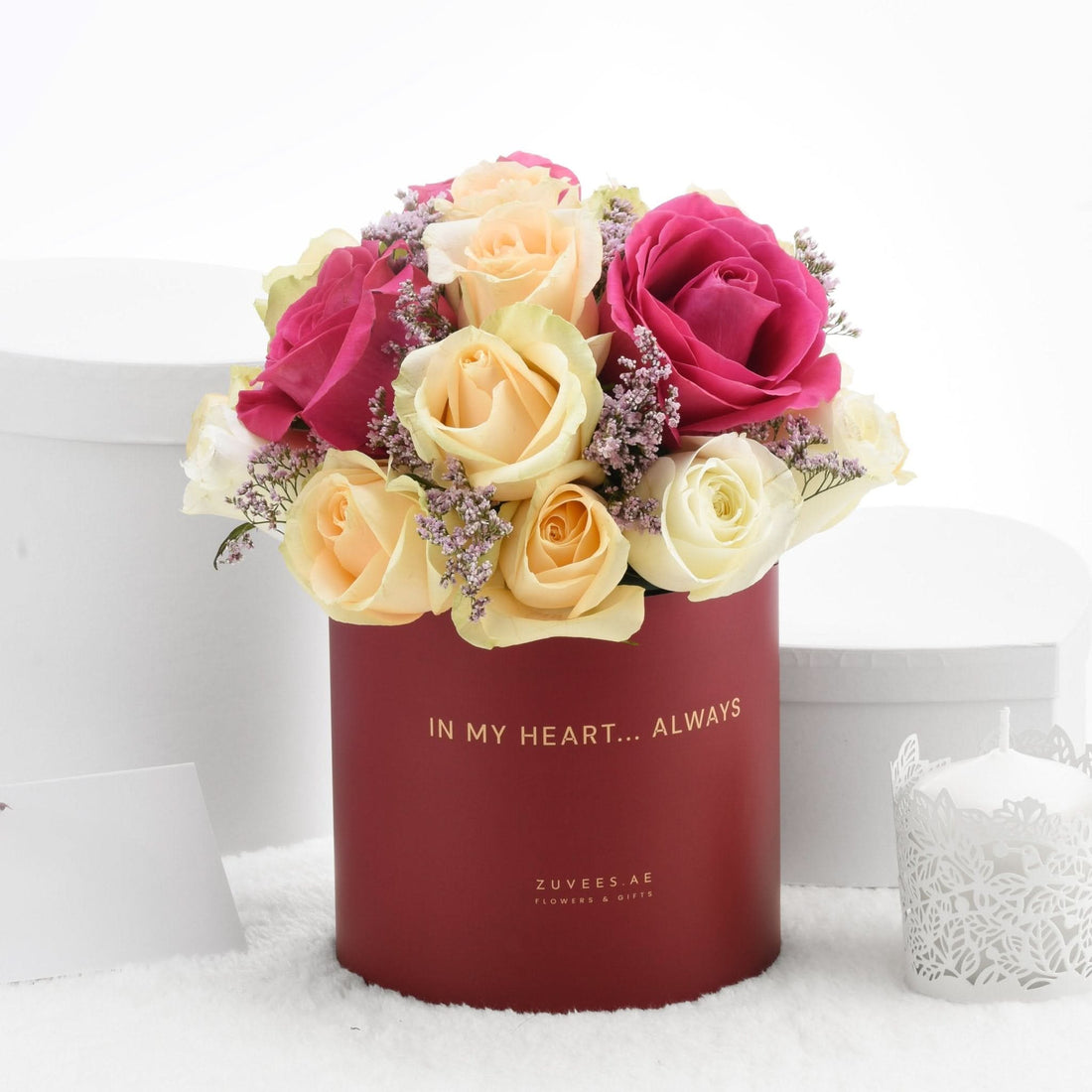 Vibrant pink, yellow, and white roses in elegant red box with gold inscription.