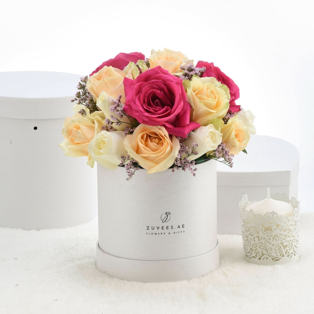 Vibrant pink and yellow roses in white box, accented with lavender sprigs.